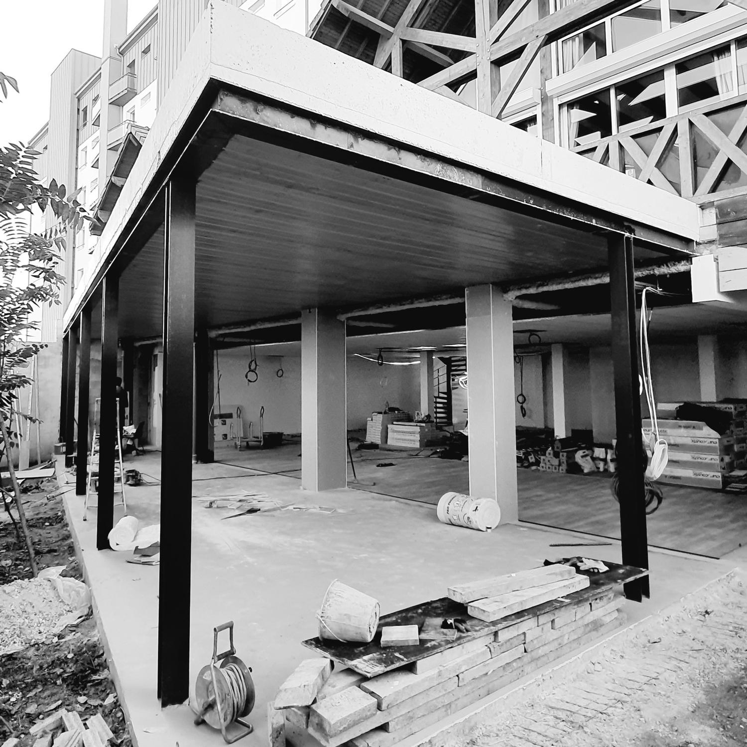 Ossature métallique et plancher créés sous un bâtiment existant, en cours de chantier