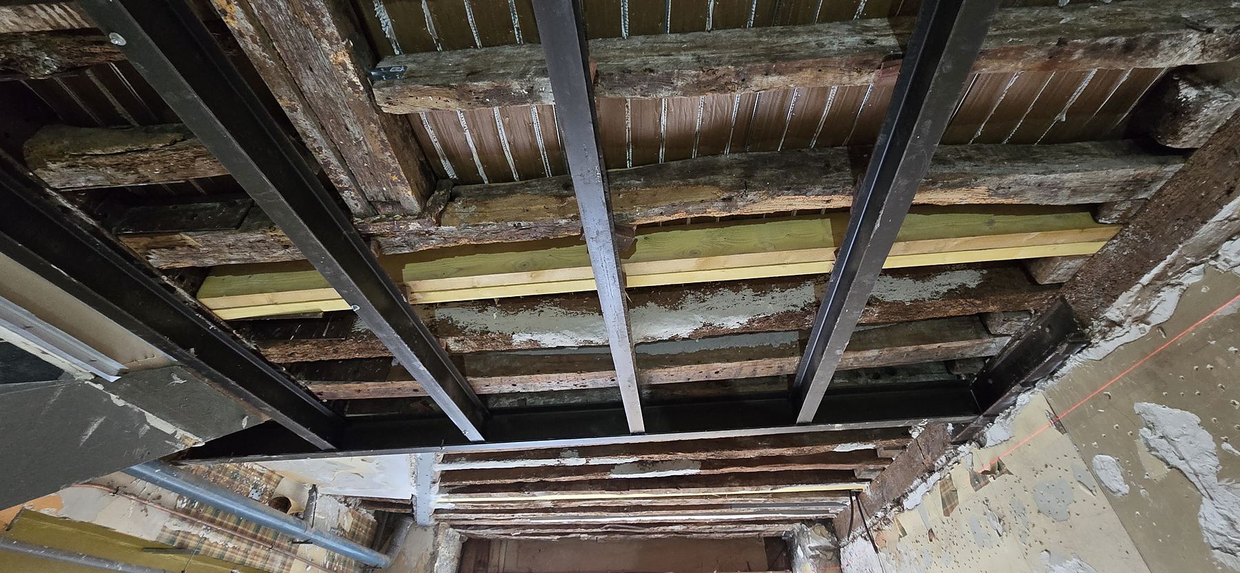 Sous-face d'un plancher ancien : solives d'origine, bois neufs et poutres métalliques de renfort