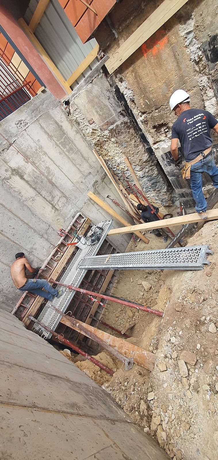 Compagnons au travail dans une fouille, butons et étais sous les murs existants
